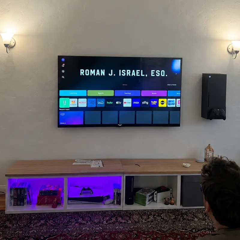 Xbox Series X mounted on wall to the right of TV, no visible cables