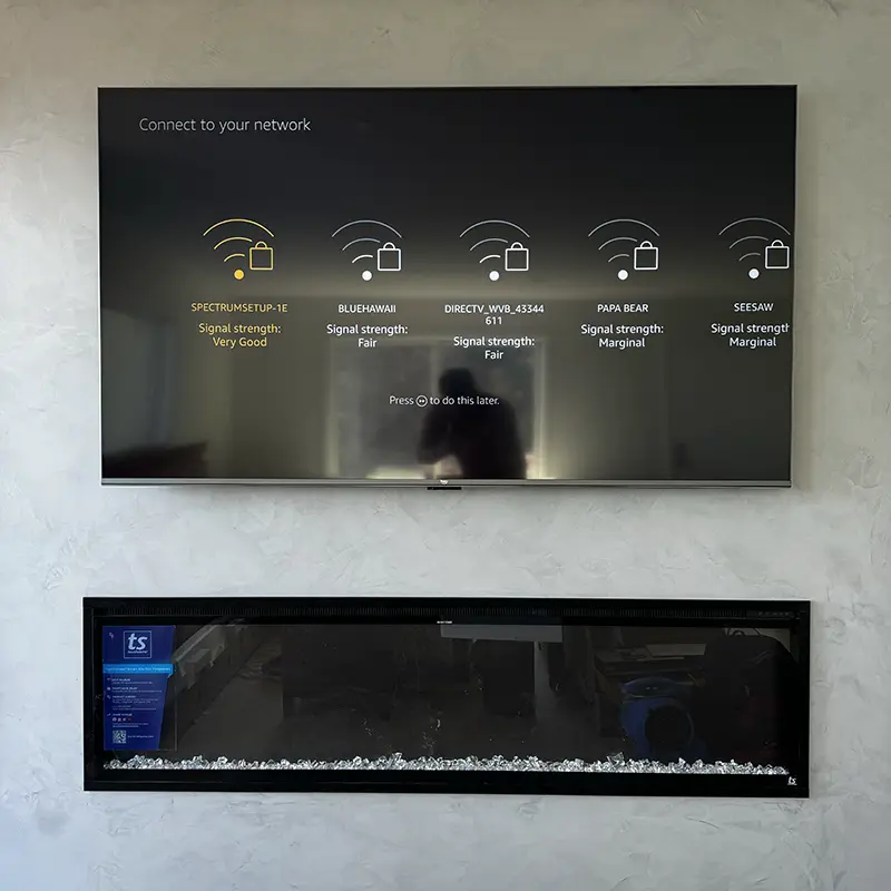TV mounted above electric fireplace with outlet hidden behind, no visible wires