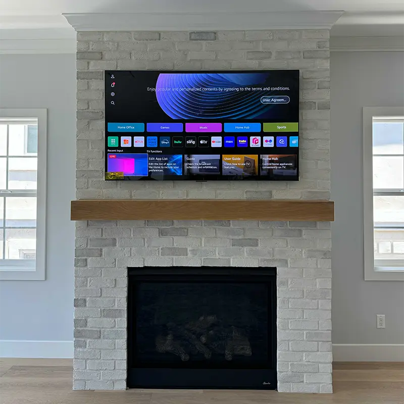 TV on full-motion mount above white brick fireplace, cables hidden in wall