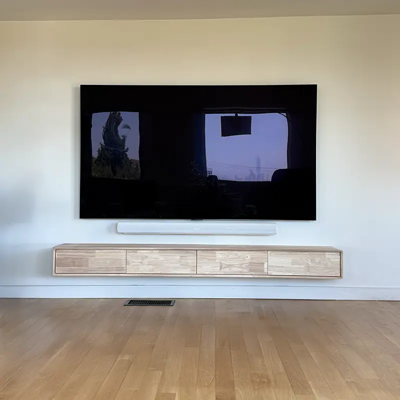 Wall-mounted TV with soundbar and floating media shelf, all cables routed through wall