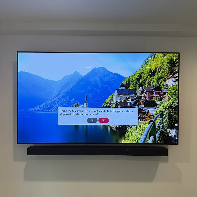 TV and soundbar mounted together with outlet directly behind TV, no visible cables